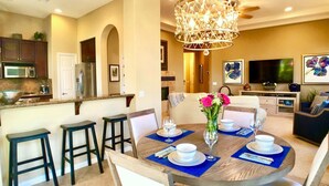 A dining area with a round table, chairs, and a chandelier.