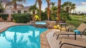 Piscina y spa privados en PGA West, rodeados de palmeras y un césped cuidado.
