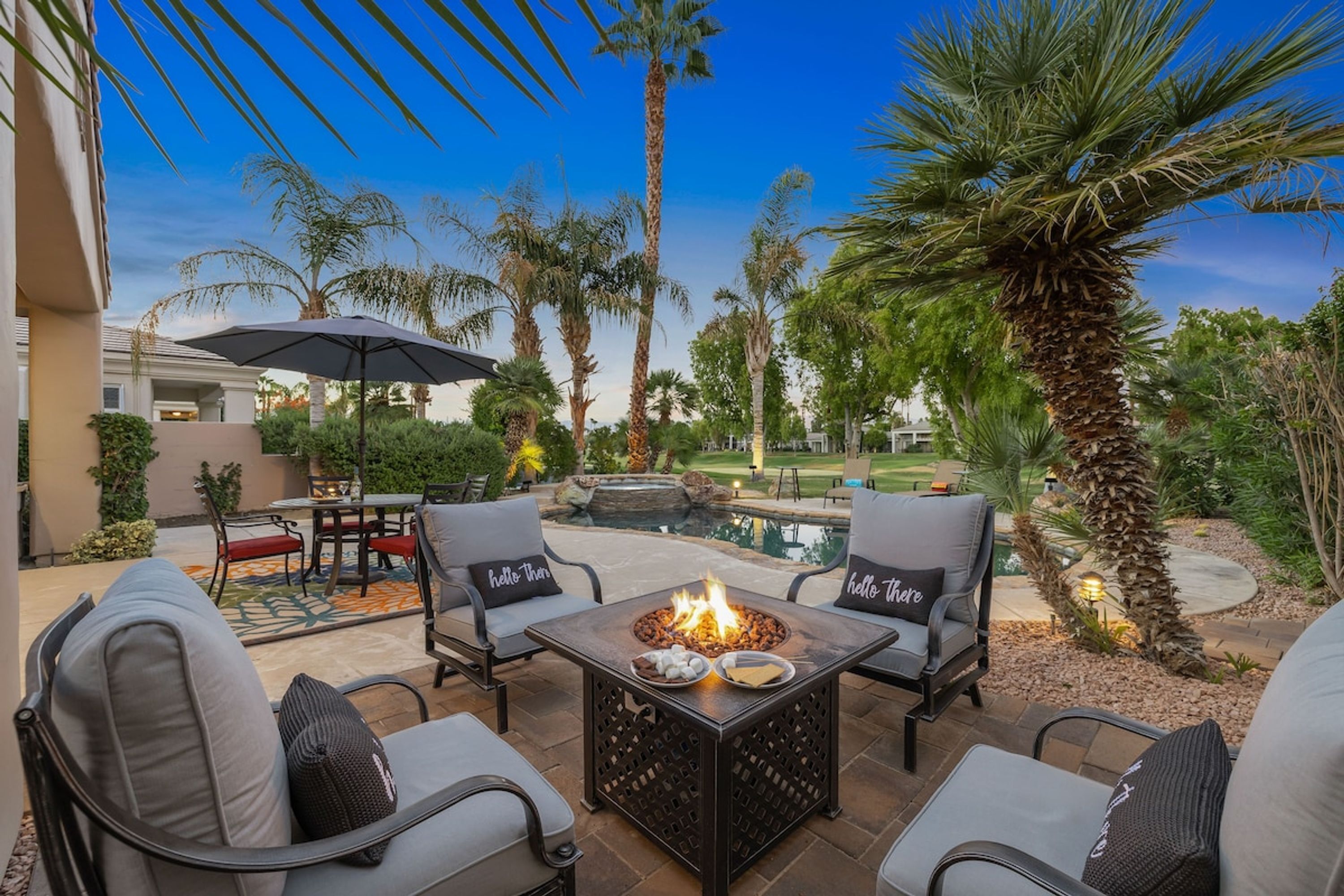 An outdoor patio with a fire pit, seating, and a pool.