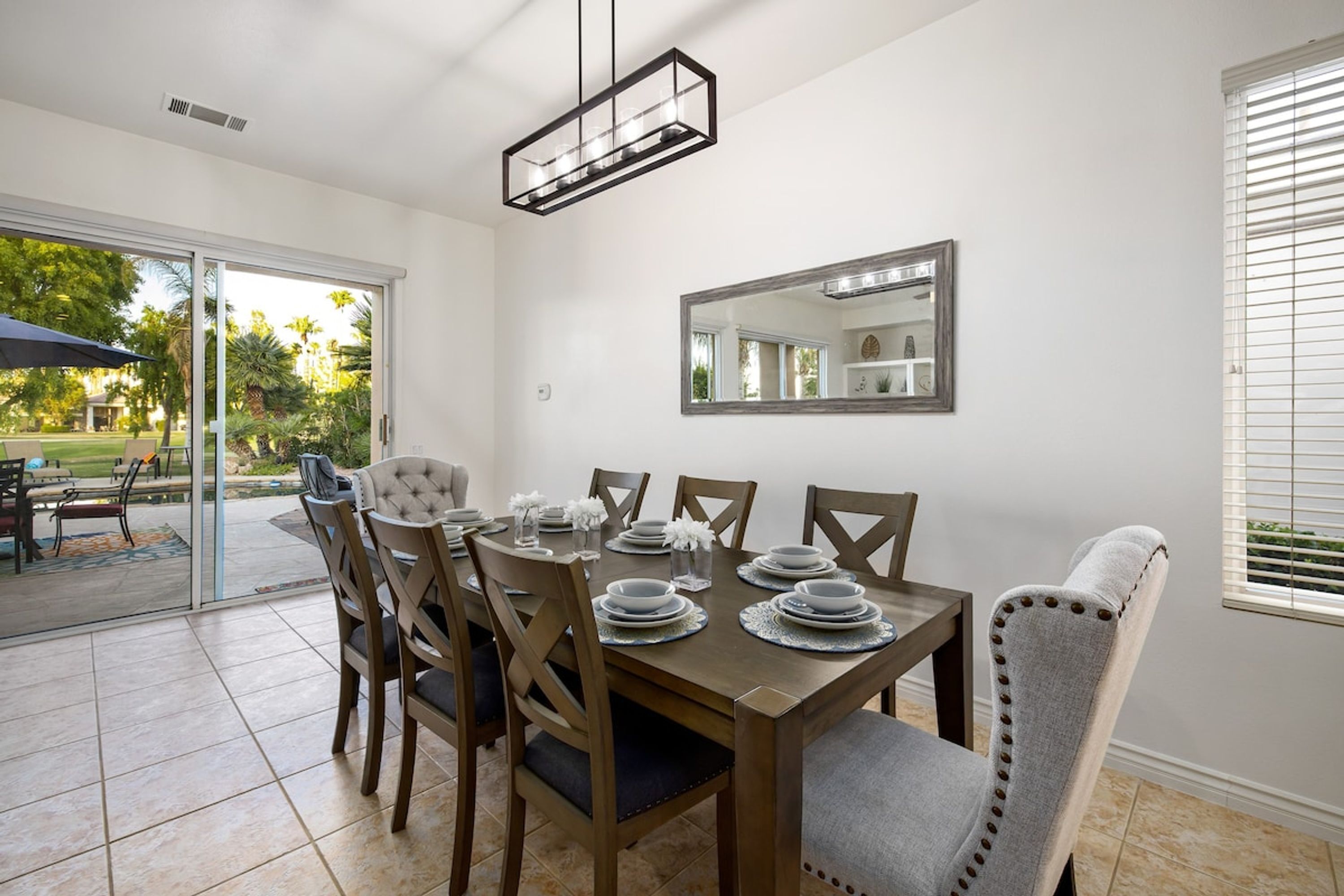 A dining area with a wooden table set for four, surrounded by upholstered chairs.