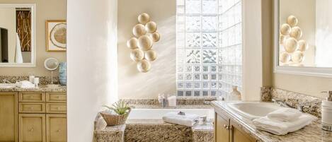 Une salle de bain avec une baignoire, un lavabo et une fenêtre en verre dépoli.