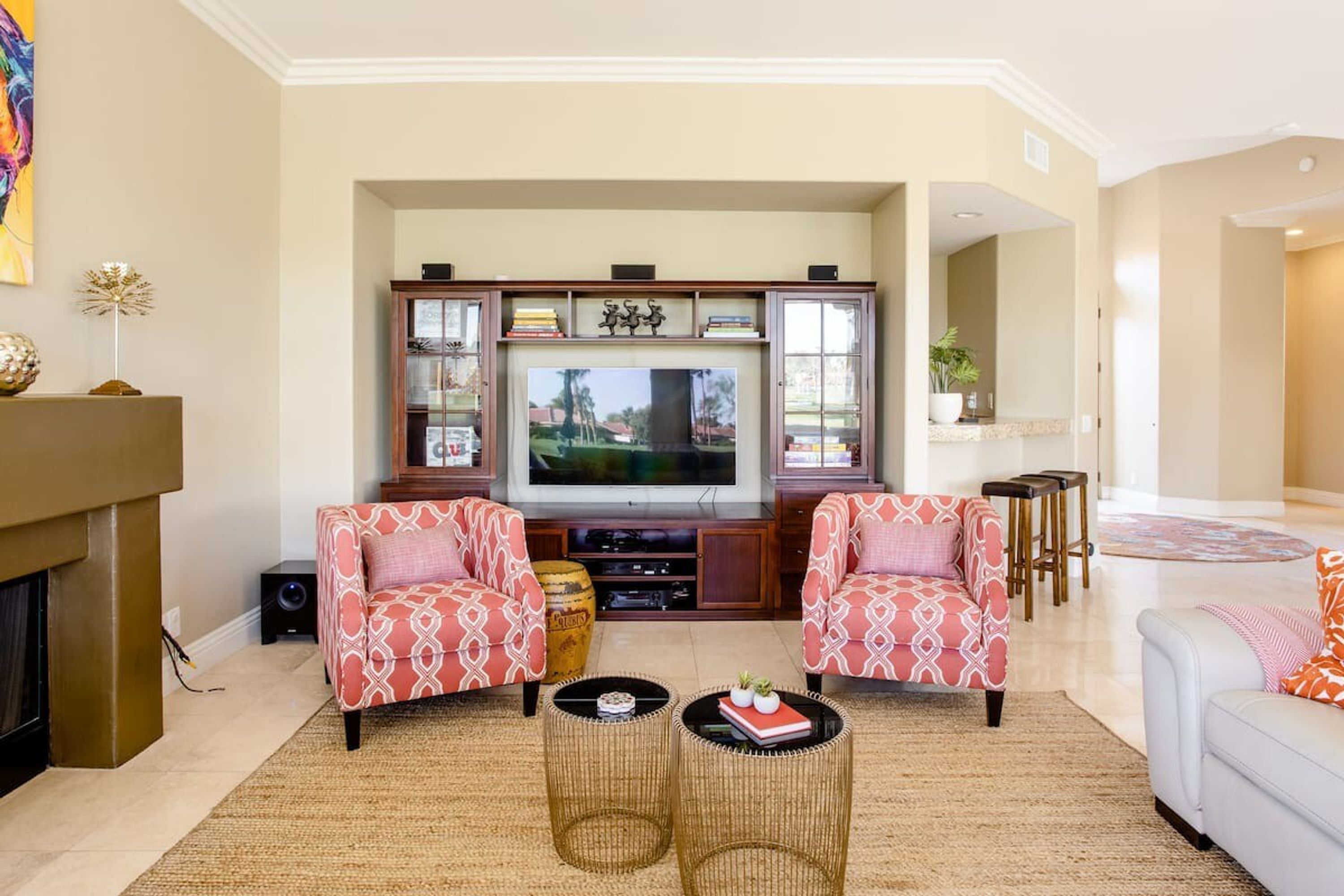 A living room with a fireplace, two patterned armchairs, a television, and a coffee table.