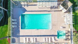 Vista aérea de un área de piscina con una pileta rectangular, varias sillas de descanso y un pequeño jacuzzi.