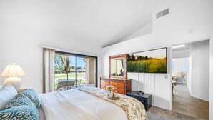 Un dormitorio moderno con una cama grande, un aparador, un televisor y vistas al exterior.