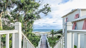 A wooden staircase leading to a beach with a view of the ocean.