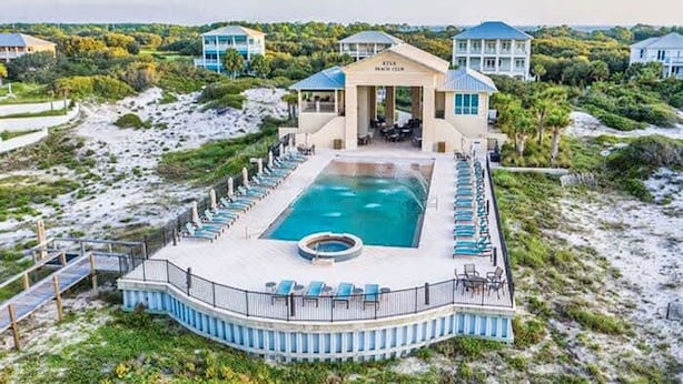 A resort with a large pool, lounge chairs, and a covered area.