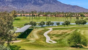 A golf course with a mountain backdrop, a water feature, and a solar panel structure. - Fairway-view 3 Bedroom Condo in Palm Desert (Palm Desert)