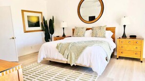 A bedroom with a bed, bedside tables, a mirror, a dresser, and a patterned rug. - Fairway-view 3 Bedroom Condo in Palm Desert (Palm Desert)