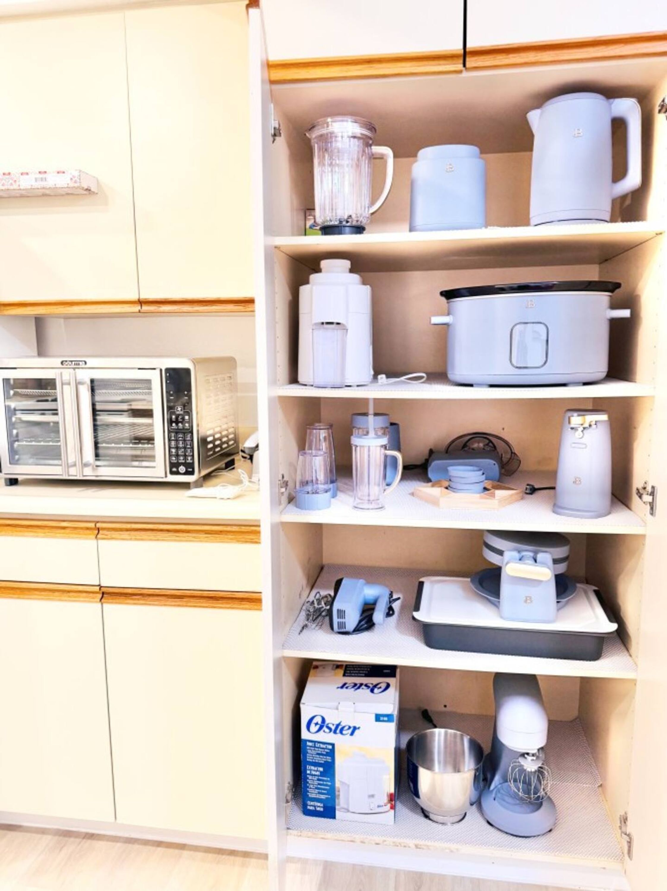 Una cocina con microondas, tostadora y diversos electrodomésticos en estantes.