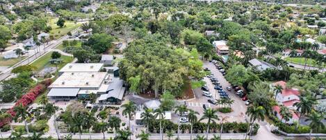 Vista aérea de una zona residencial con varios edificios, carreteras y palmeras.