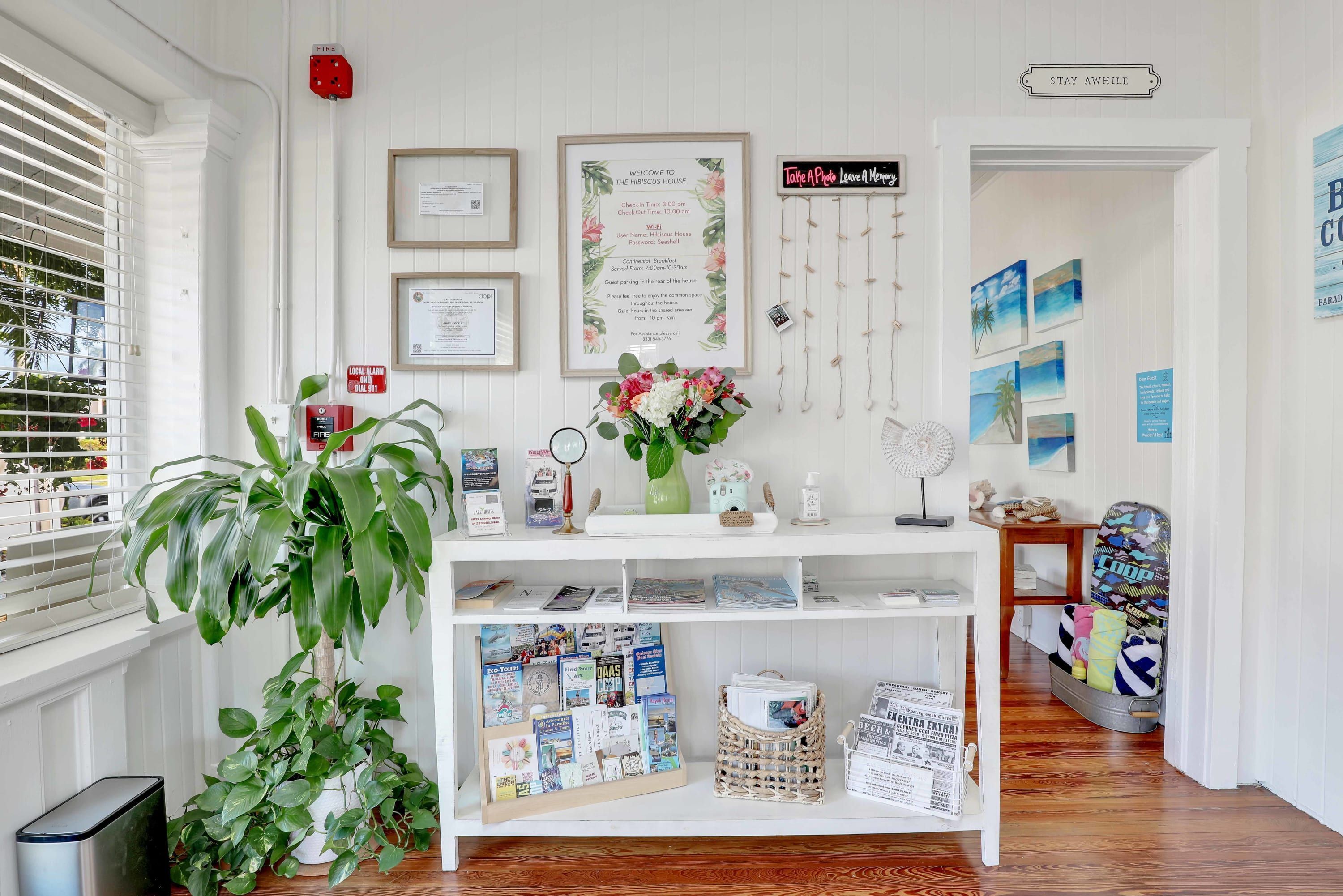 A reception desk with framed welcome signs, a fire alarm, and a wall with framed artwork.