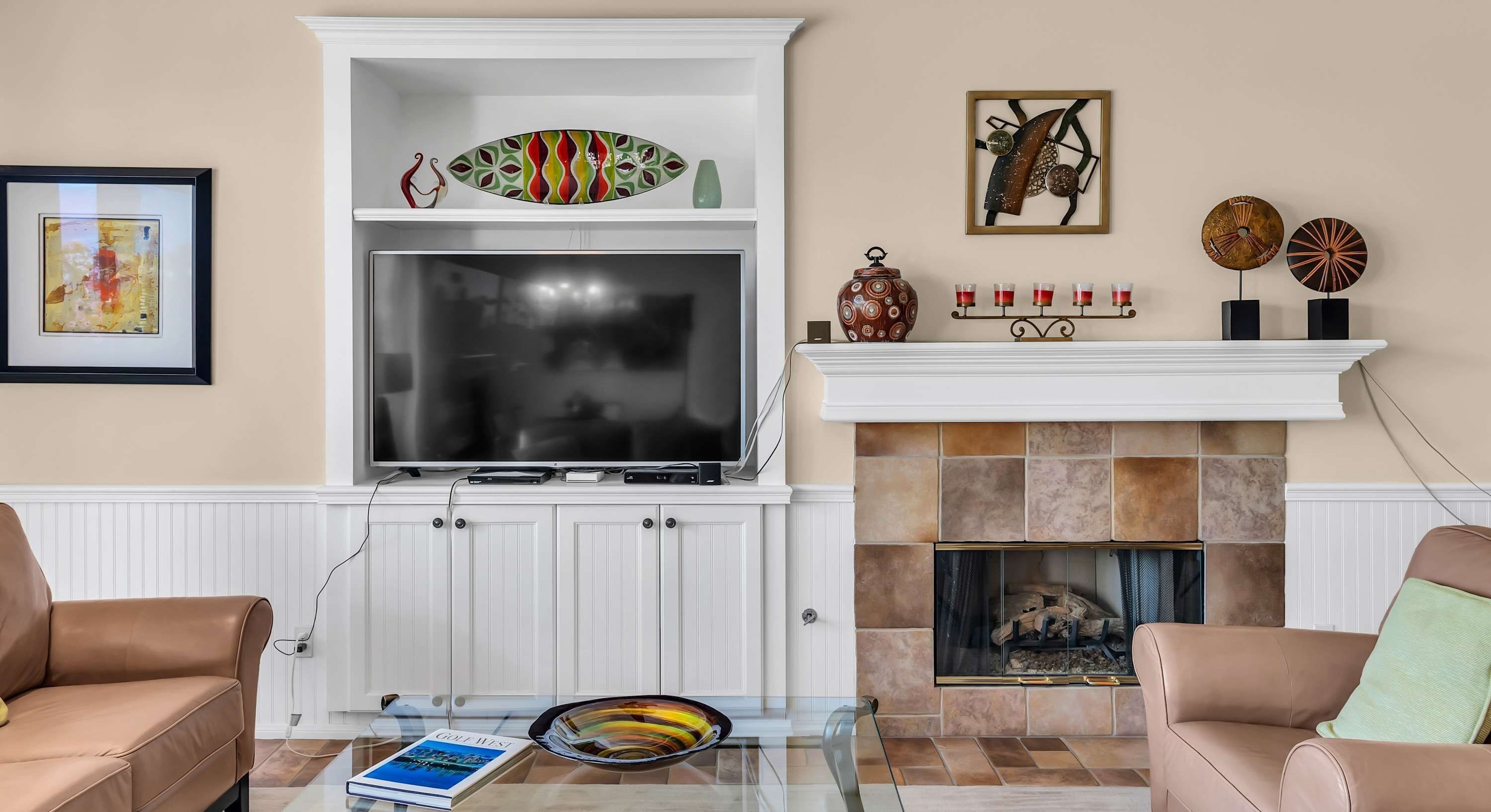 Una sala de estar con chimenea, televisor y una mesa de centro de vidrio.