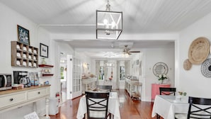 Una cocina amplia con armarios blancos, encimera de madera y comedor con mesa y sillas.