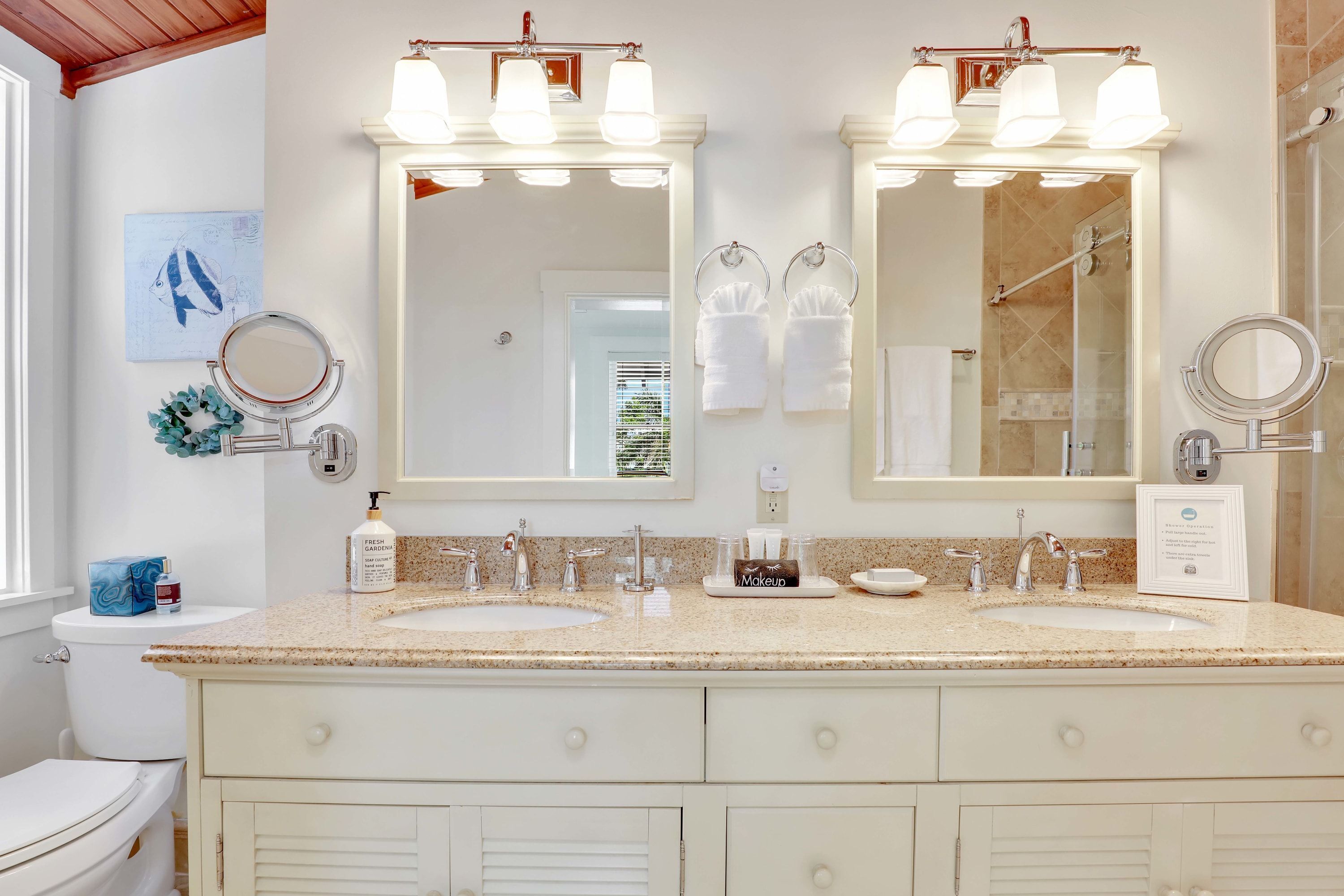 Une salle de bain avec deux lavabos, un grand miroir et une douche.