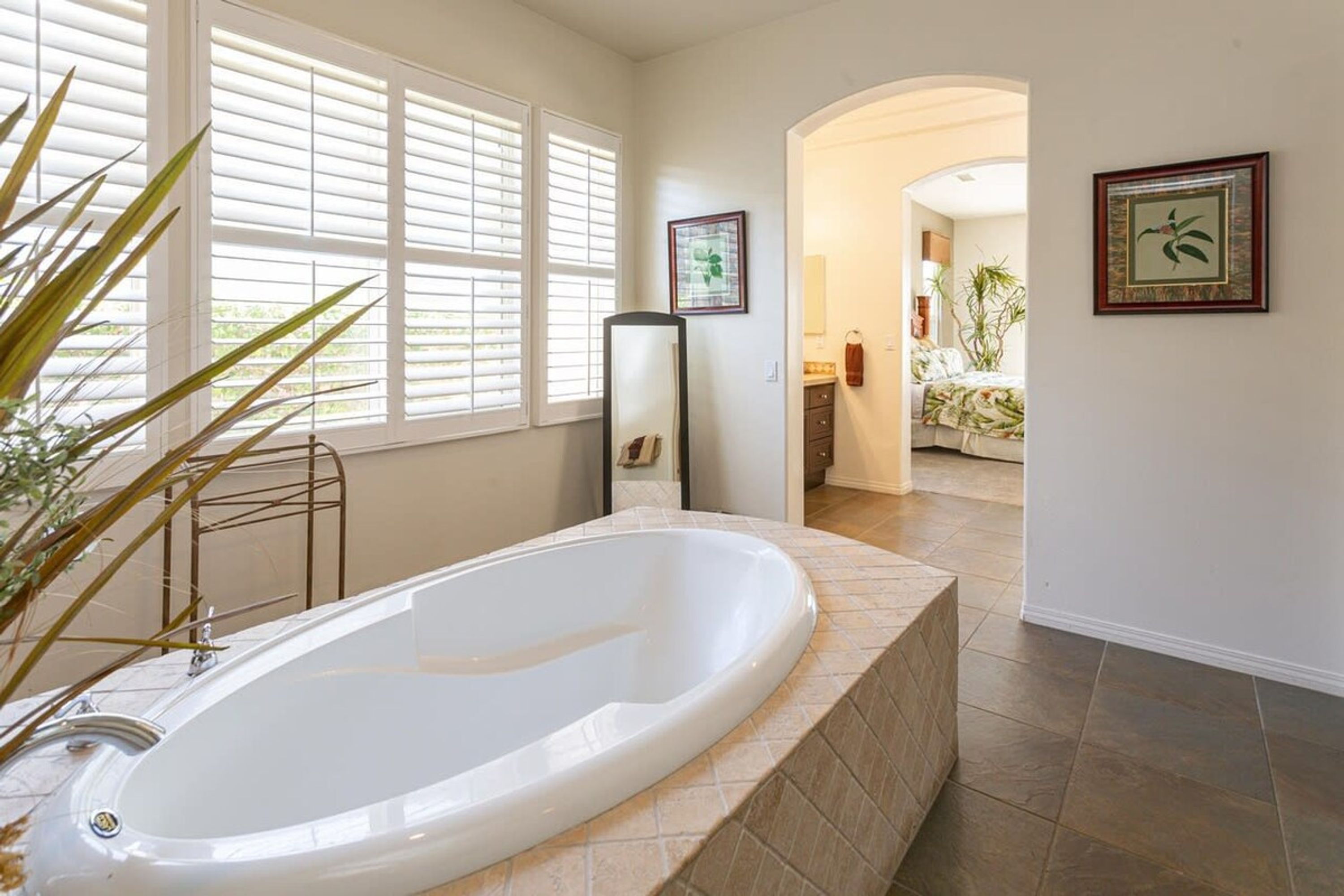 A spacious bathroom with a large bathtub, a walk-in shower, and a window with blinds.