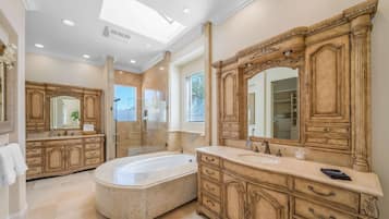 A luxurious bathroom with a large bathtub, double sinks, and ornate cabinetry.