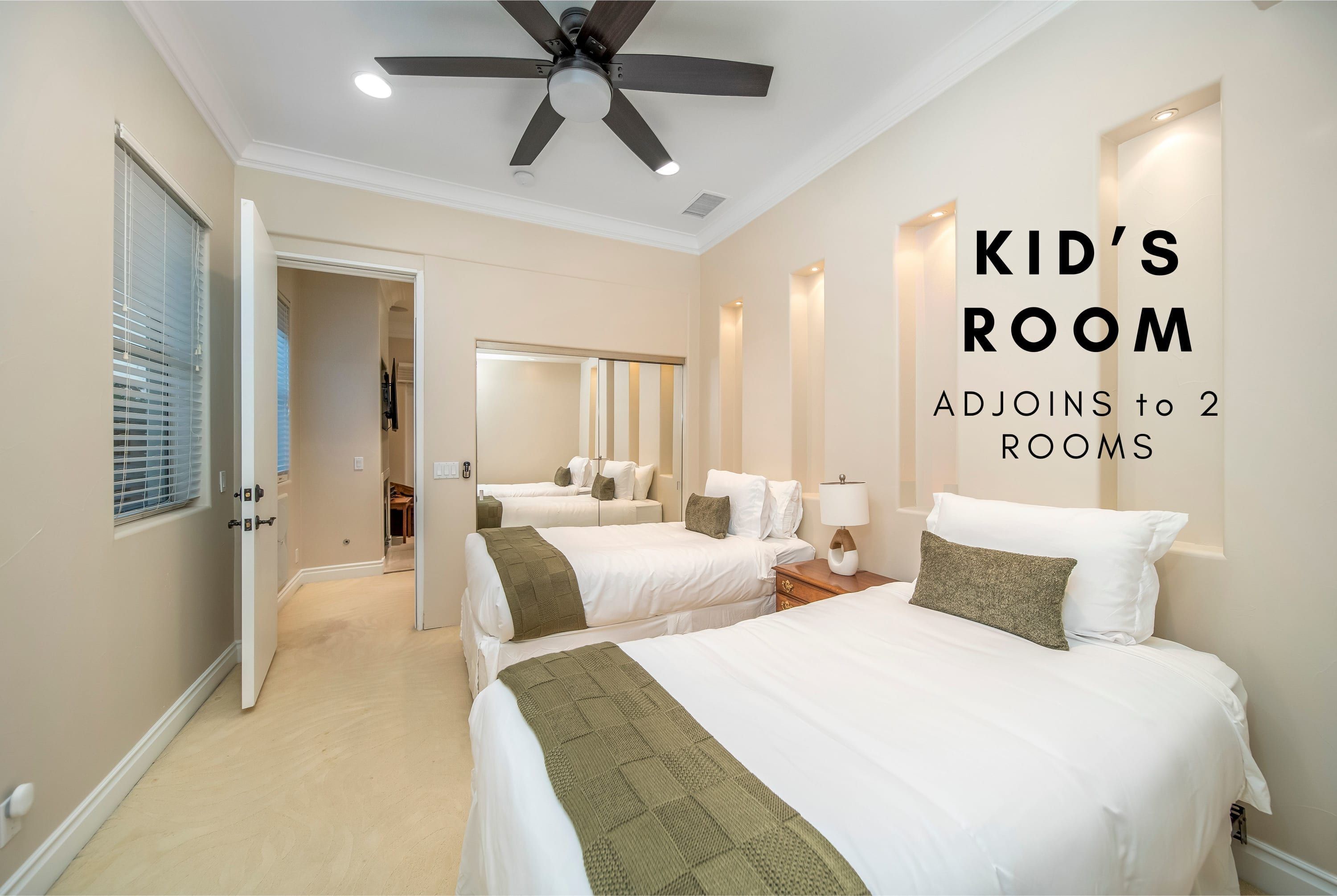 A kid's room with two beds, a ceiling fan, and a mirror.