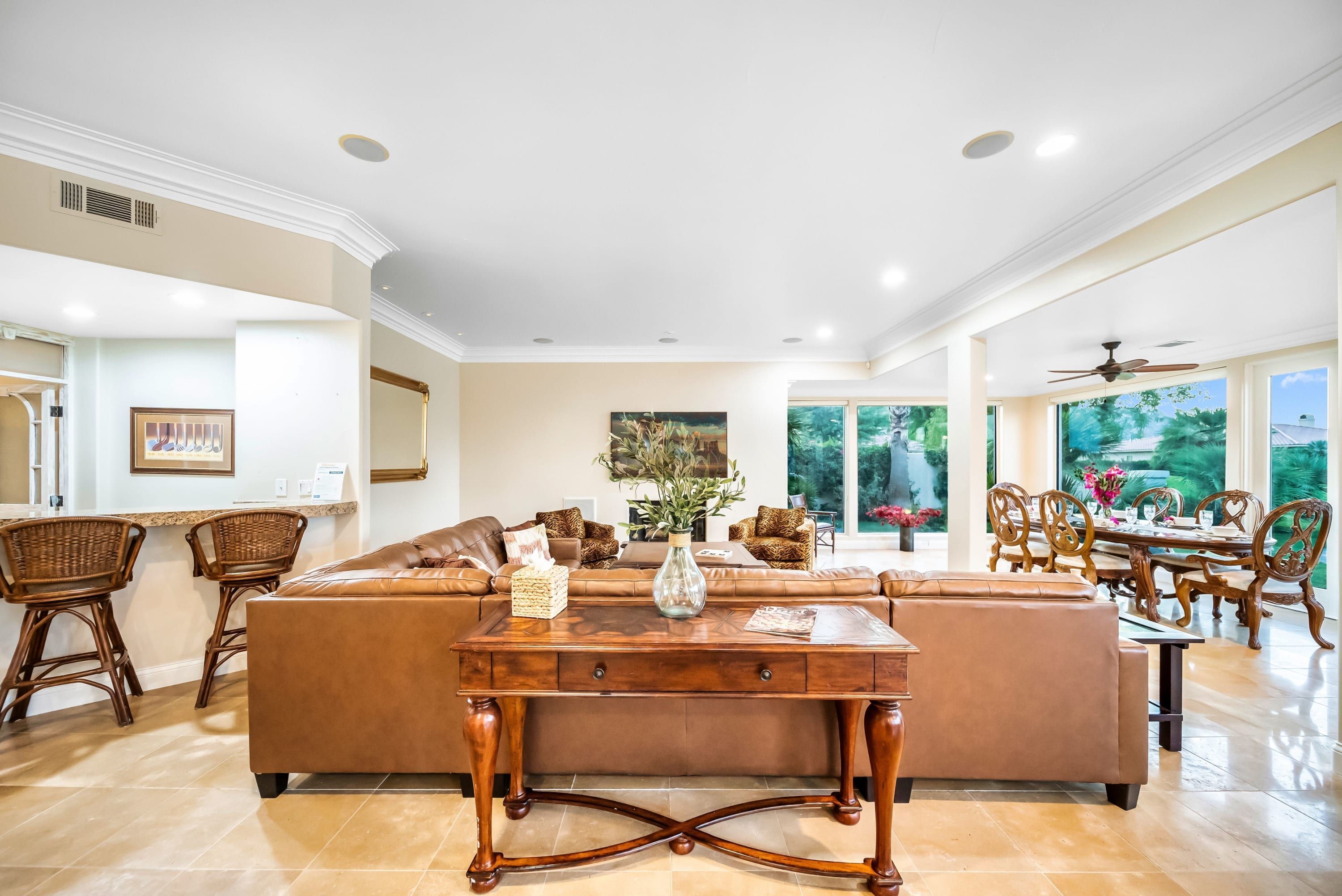 Una sala de estar amplia con un sofá marrón grande, una mesa de centro de madera y un comedor con sillas y una mesa de madera.