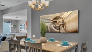 A dining area with a wooden table, four chairs, and a large abstract painting on the wall. - Jedi Training Camp Top Rated 5 Star Villa (Kissimmee)