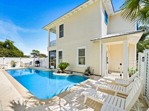 Uma casa de dois andares com piscina, área de estar ao ar livre e pátio cercado.