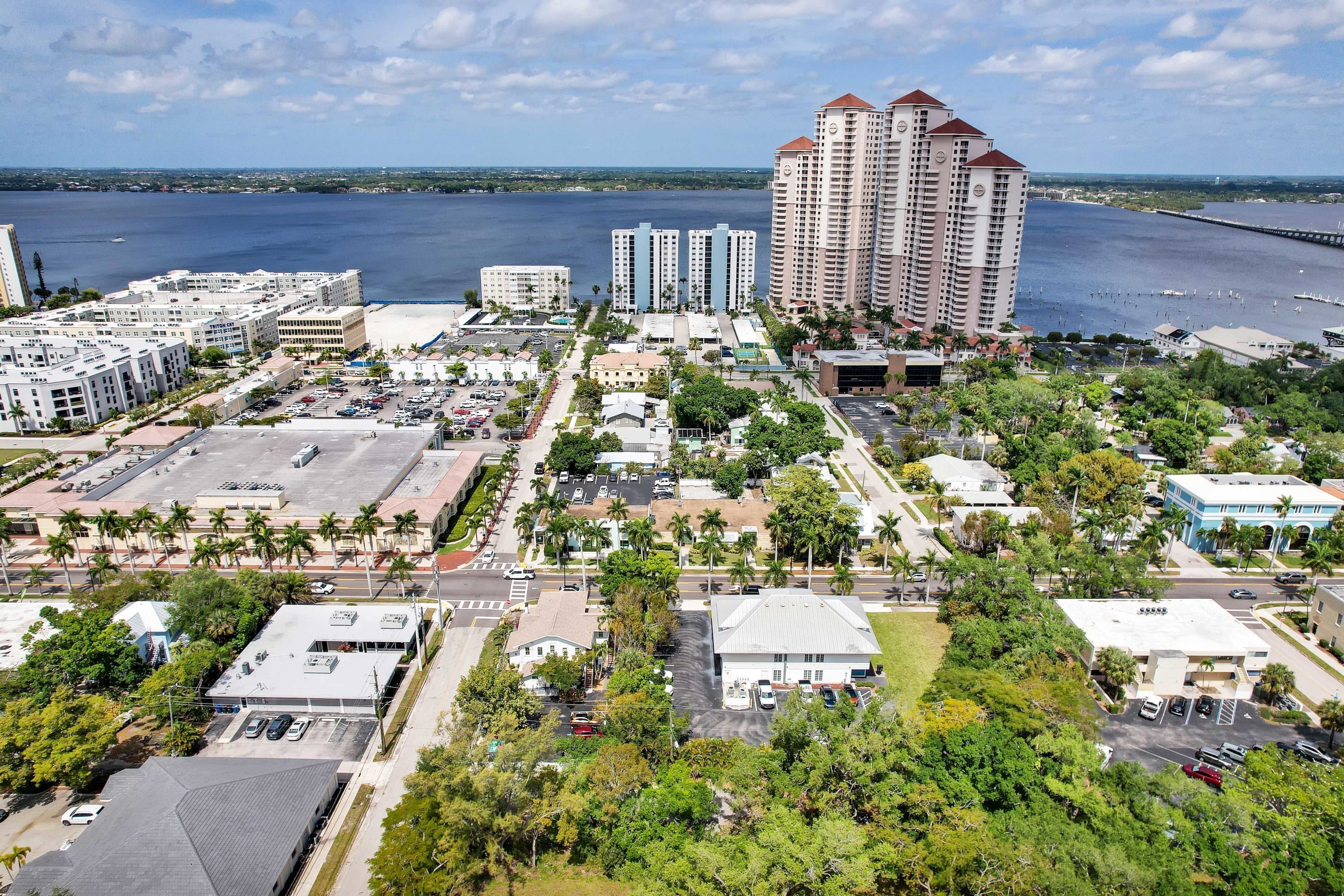 An aerial view of a coastal city with high-rise buildings, a marina, and a parking lot.