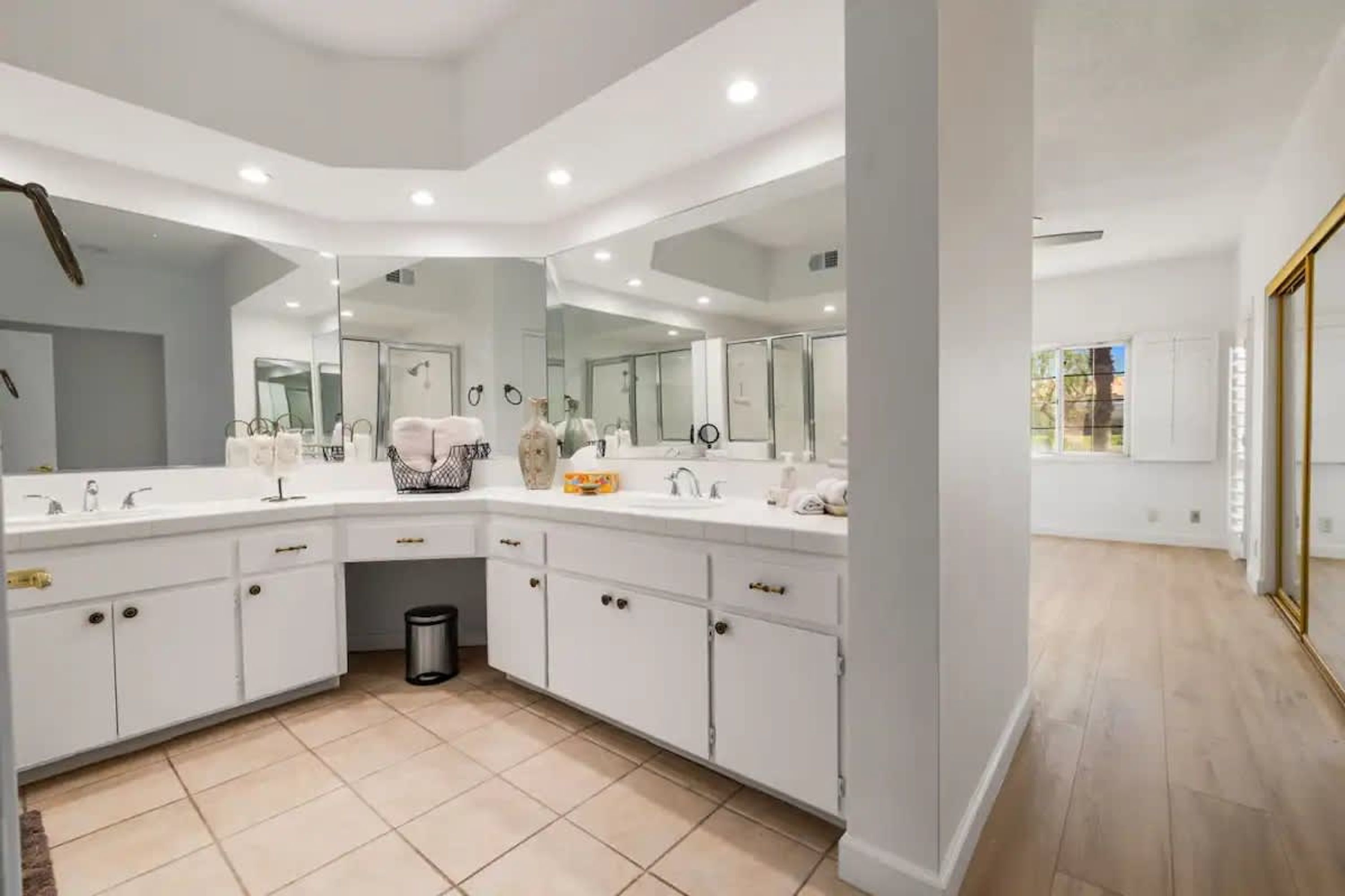 Une salle de bain moderne avec un grand meuble-lavabo, un miroir et une poubelle.