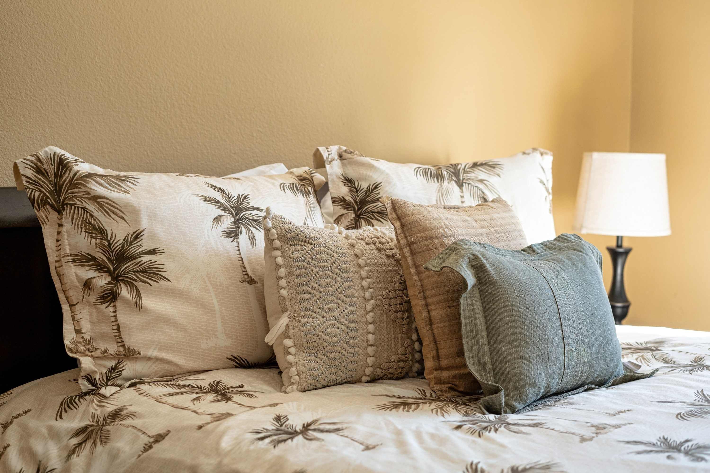 A bed with multiple pillows, a lamp, and a wall.