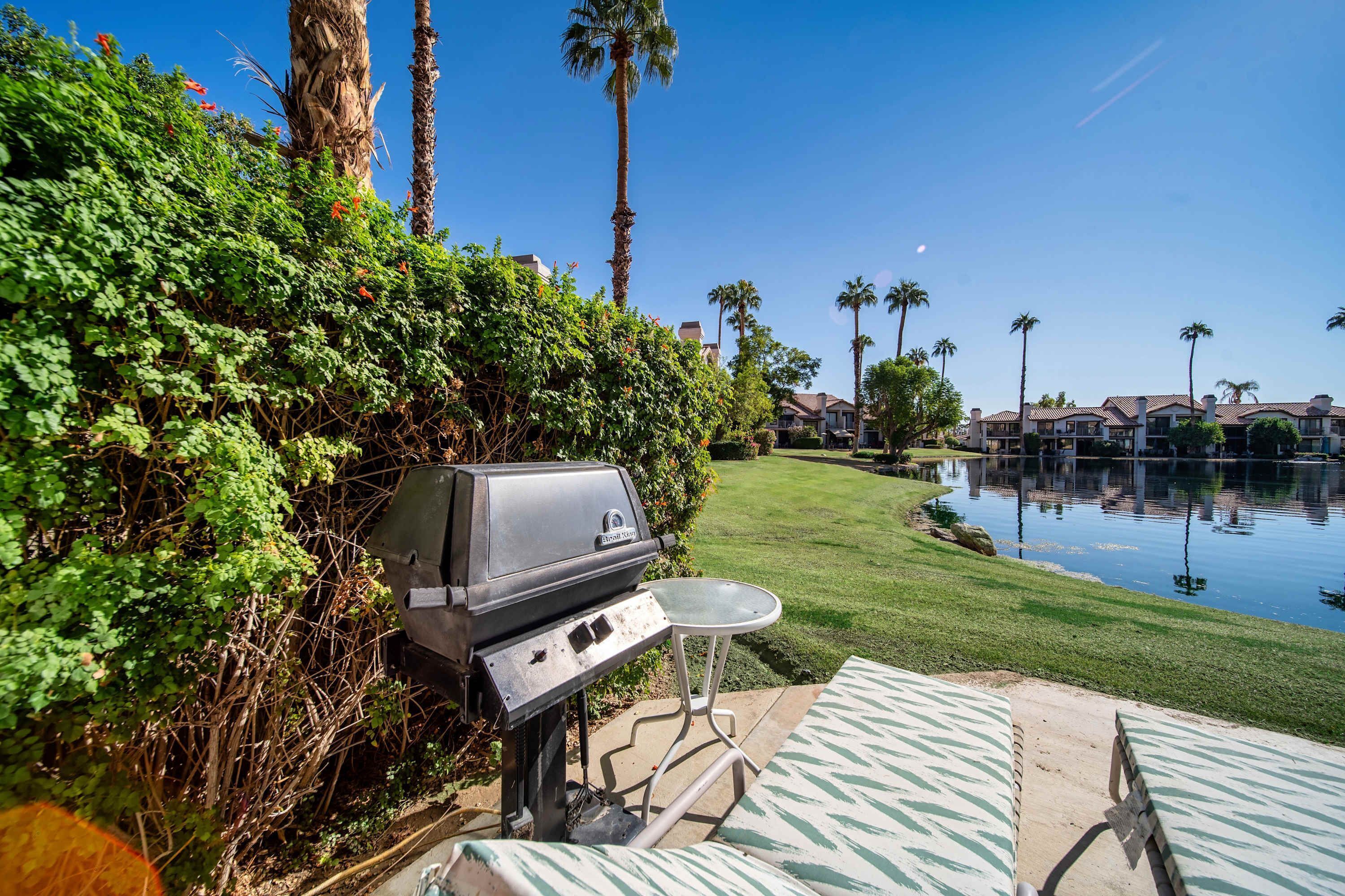 A backyard with a grill, a pool, and a lawn.