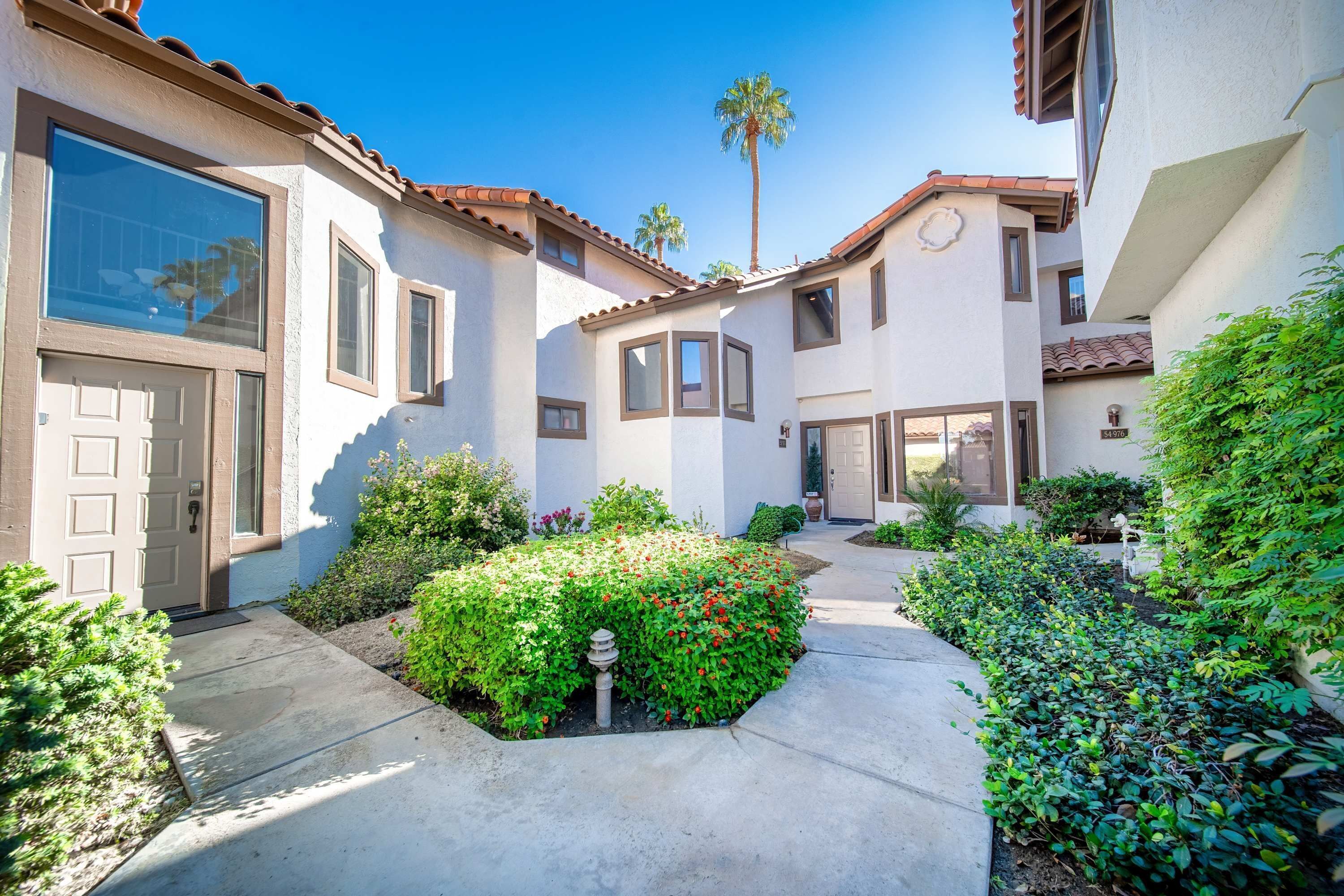 A residential building with a patio, a palm tree, and a well-maintained garden.