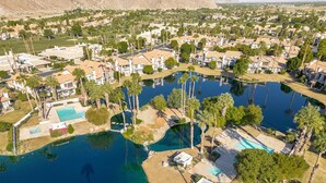 Vista aérea de una zona residencial con múltiples piscinas, palmeras y casas.