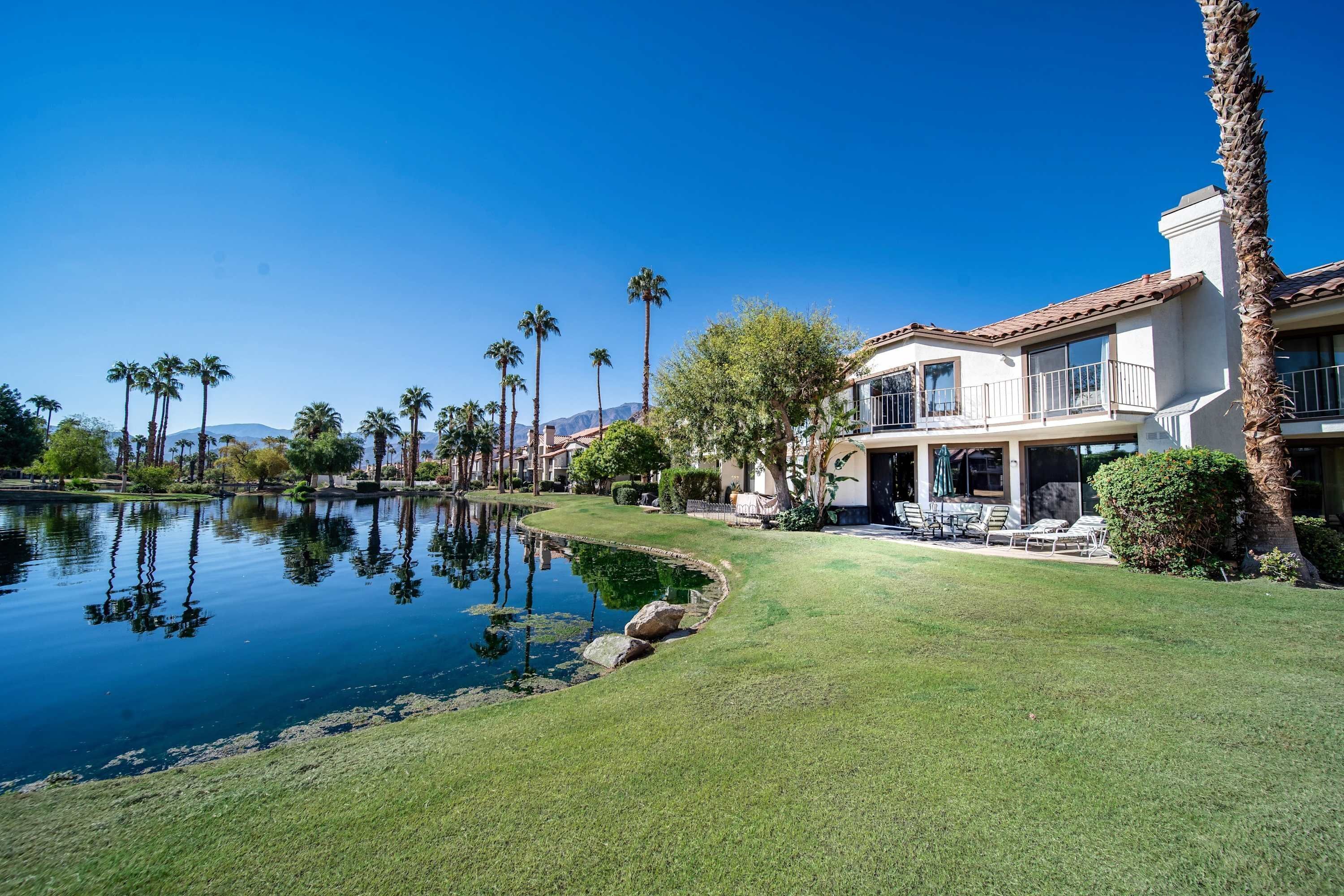 A house with a pool, palm trees, and a well-maintained lawn.
