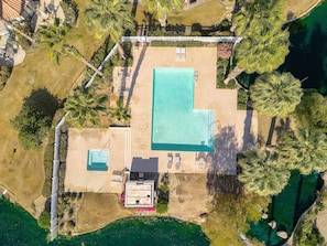 Vue aérienne d’un complexe hôtelier avec une piscine, des chaises longues et un petit bâtiment.
