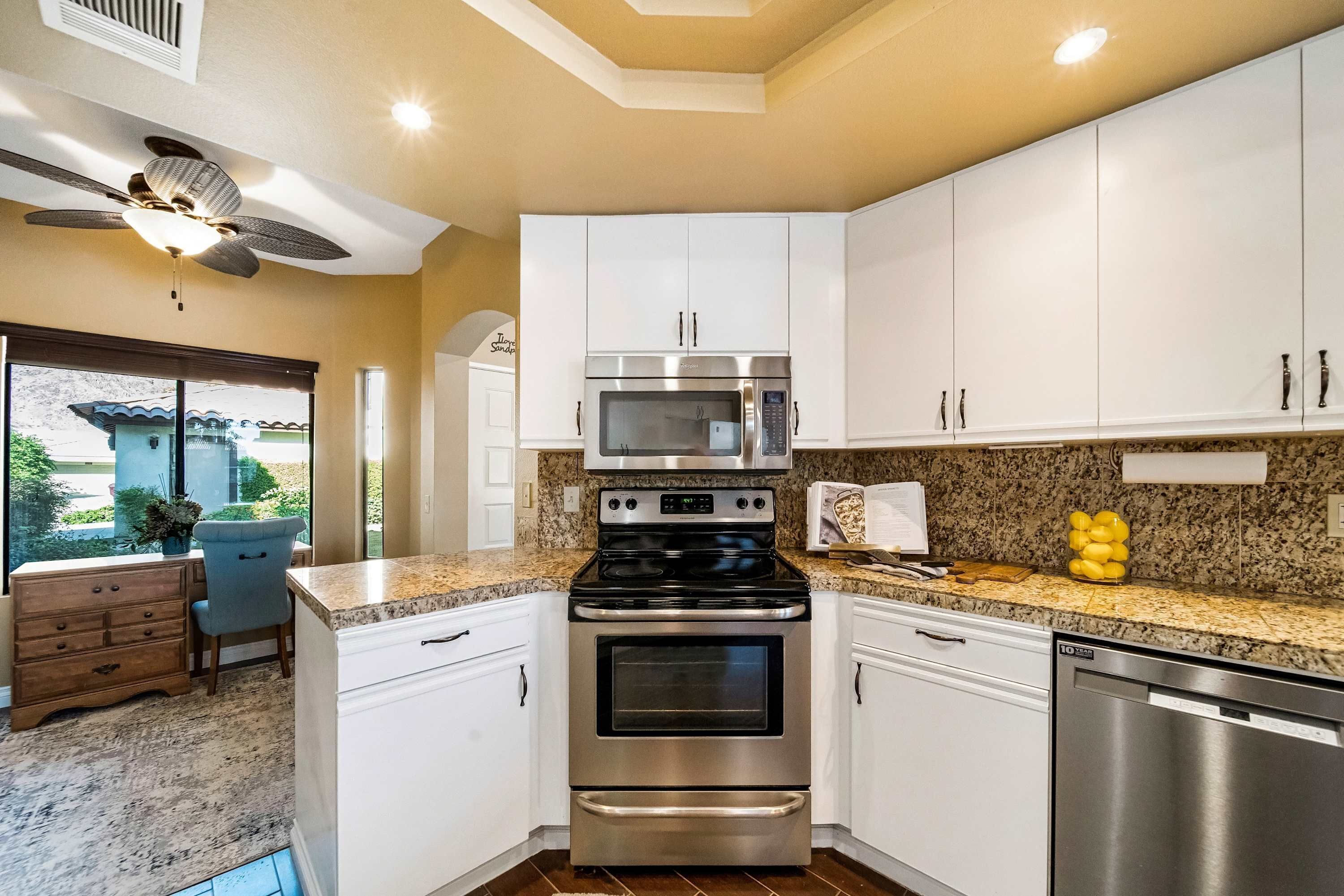 A kitchen with white cabinets, a stainless steel oven, a microwave, and a dishwasher.