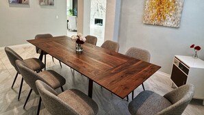 Un espace repas moderne avec une table en bois, six chaises rembourrées et un vase de fleurs.