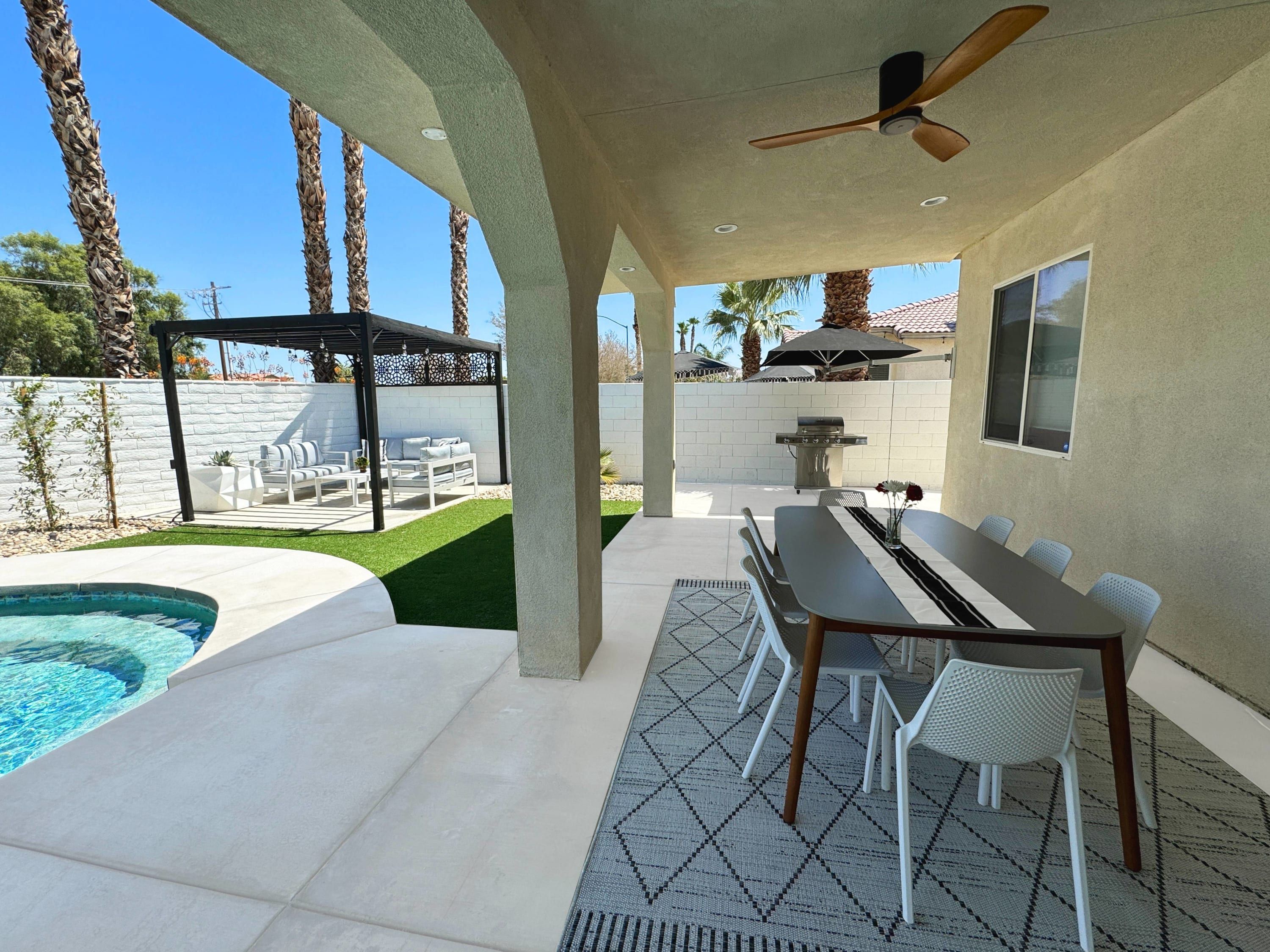 Una veranda esterna con piscina, zona pranzo e barbecue.