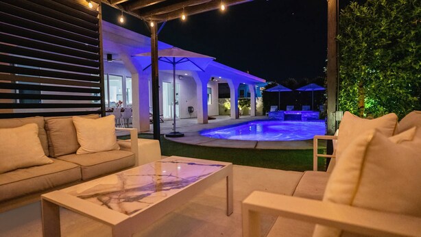 Un espace extérieur aménagé avec une terrasse, une piscine, des sièges et un coin salon abrité.