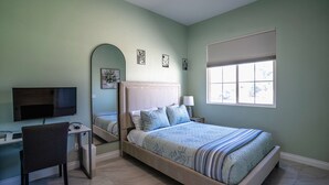 Une chambre à coucher avec un lit, un bureau, une chaise, un téléviseur et une fenêtre.