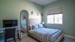 A bedroom with a bed, a desk, a chair, a TV, and a window. - Palm Luxe Estate Luxury Desert Retreat With Pool (Indio)