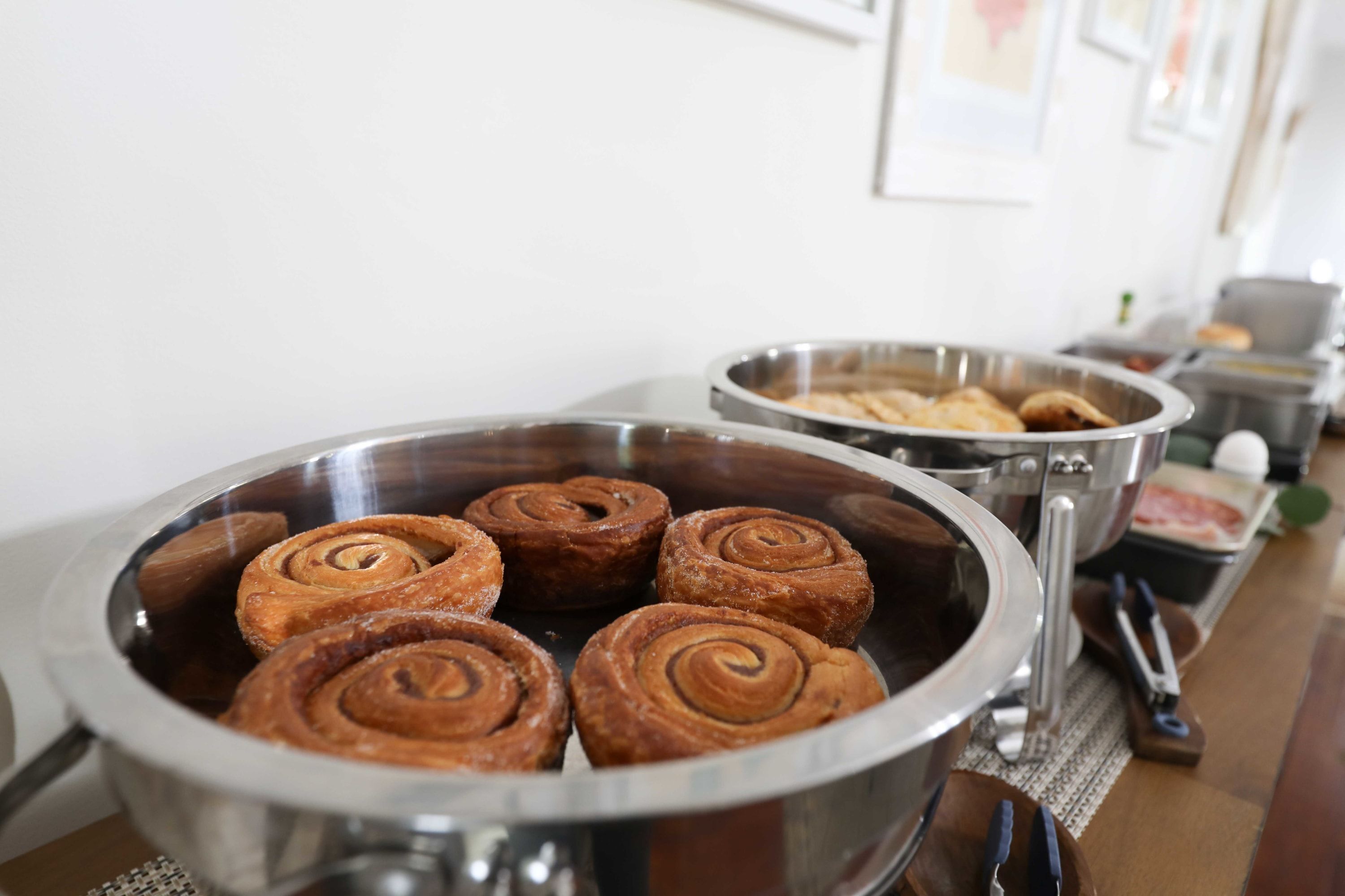 Een buffet met diverse gerechten, waaronder kaneelbroodjes en andere gebakjes.