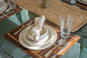 Taula preparada amb plats blancs, un got transparent i una tovallola plegada amb una forma decorativa.