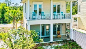 A two-story house with a balcony, large windows, and a fenced yard. - Gulf Shores Hideaway Walk to Waves Pool Golf Views (Gulf Shores)