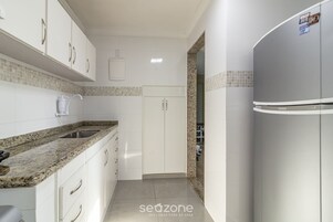 Uma cozinha moderna com armários brancos, bancada de granito e geladeira embutida.