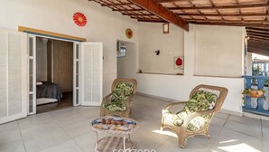 Un espacio habitable de concepto abierto con mobiliario de mimbre, una pequeña mesa con adornos y vistas al exterior.