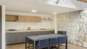 Una cocina moderna con gabinetes grises, encimera de madera y pared de piedra.