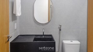 Un baño con un lavabo negro, un espejo y un inodoro.