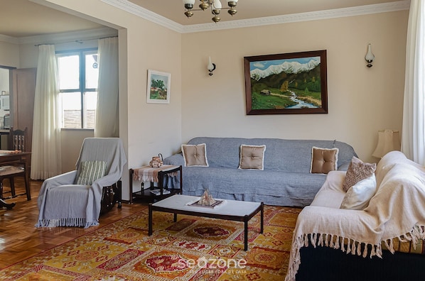 A living room with a sofa, armchairs, a coffee table, and a patterned rug.