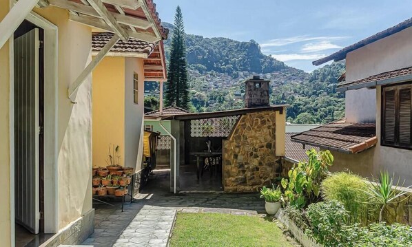 A courtyard with a stone wall, potted plants, and a view of a hillside. - Charming and Cozy House in Petropolis Vgl041 (Petrópolis)