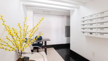 Un moderno vestíbulo de hotel con una recepción, una planta en maceta y una pared de buzones numerados.