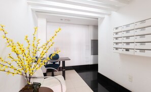 A modern hotel lobby with a reception desk, a potted plant, and a wall of numbered mailboxes. - Apt in the Center, 300m From the Beach - Vel0102 (Guarapari)
