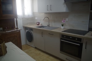 A kitchen with a washing machine, a sink, and an oven. - Charming apartment in the heart of the village, close to the beaches, with Wi-Fi and air conditioning (Cervione)